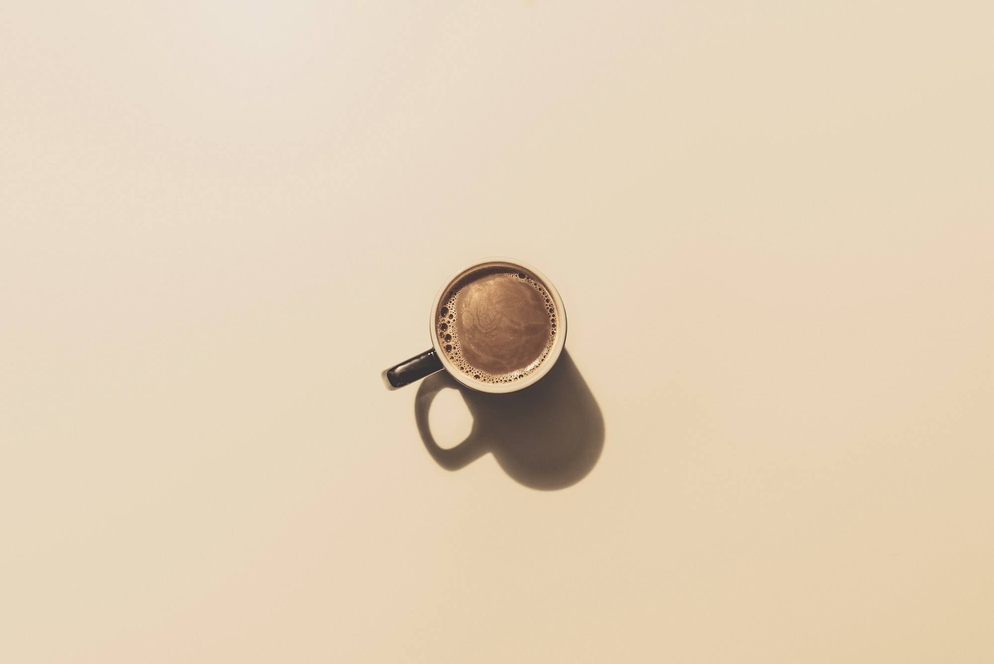 Roasted whole coffee beans in a metal scoop with ground coffee nearby