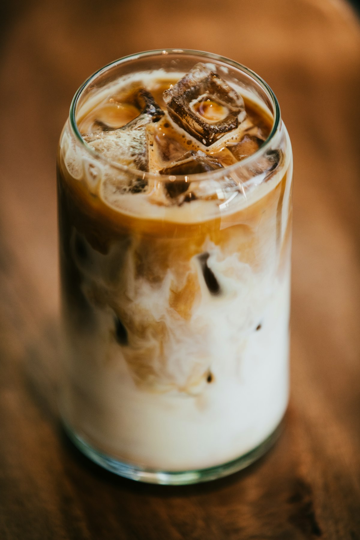 Cold brew coffee in a glass pitcher on a wooden table with ice cubes