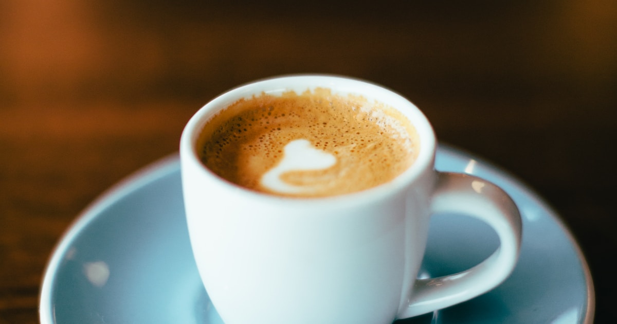Espresso shot being pulled into a glass cup from a coffee machine